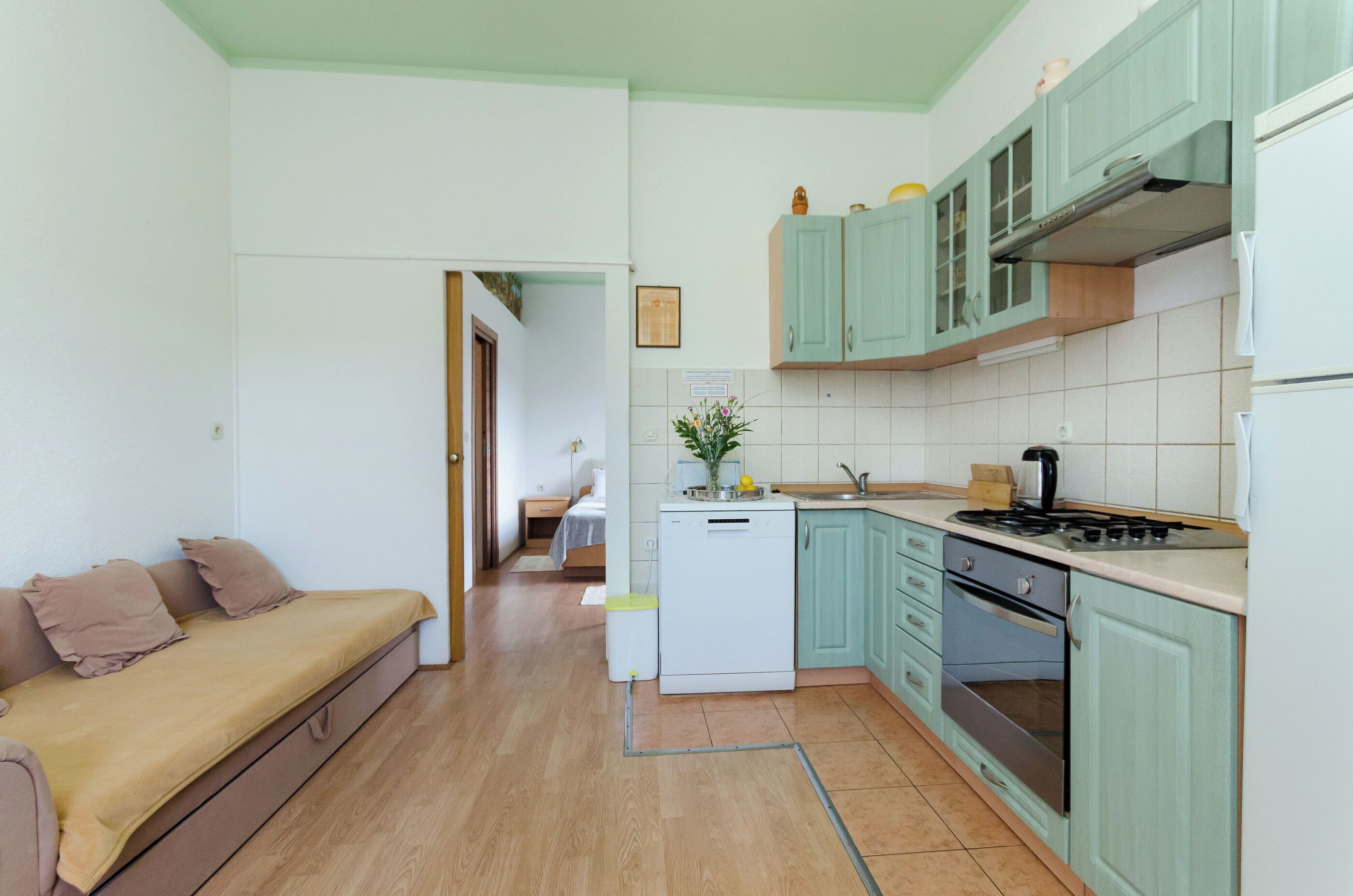 A compact kitchen with a dining area, a washing machine, and a sofa.