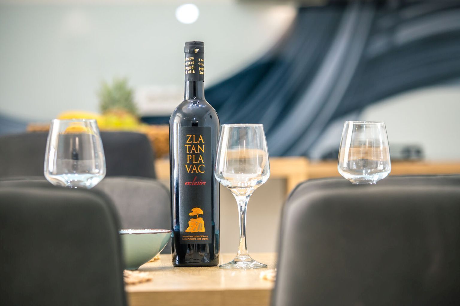 A bottle of ZLA TAN PLA VAC on a table with two empty glasses.