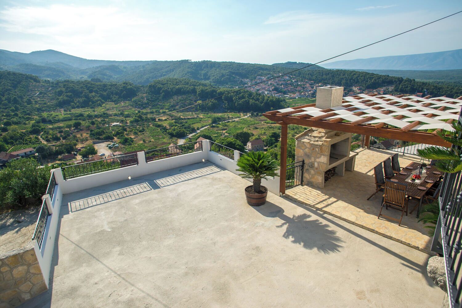 A rooftop terrace with a pergola, outdoor seating, and a potted plant.