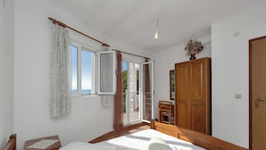 Ein Schlafzimmer mit einem Bett, einem Holzschrank, einem Stuhl und einem Fenster mit Vorhängen.