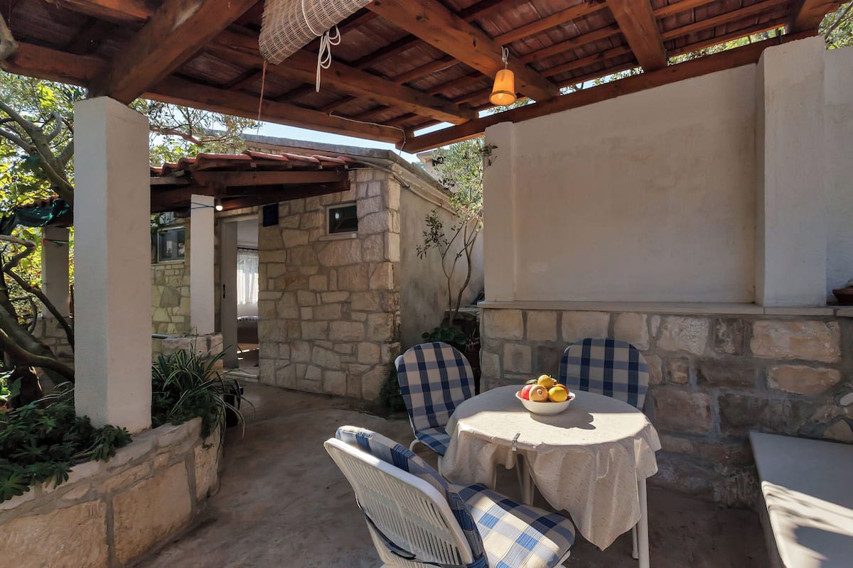 An outdoor patio with stone walls, a wooden ceiling, and checkered chairs.