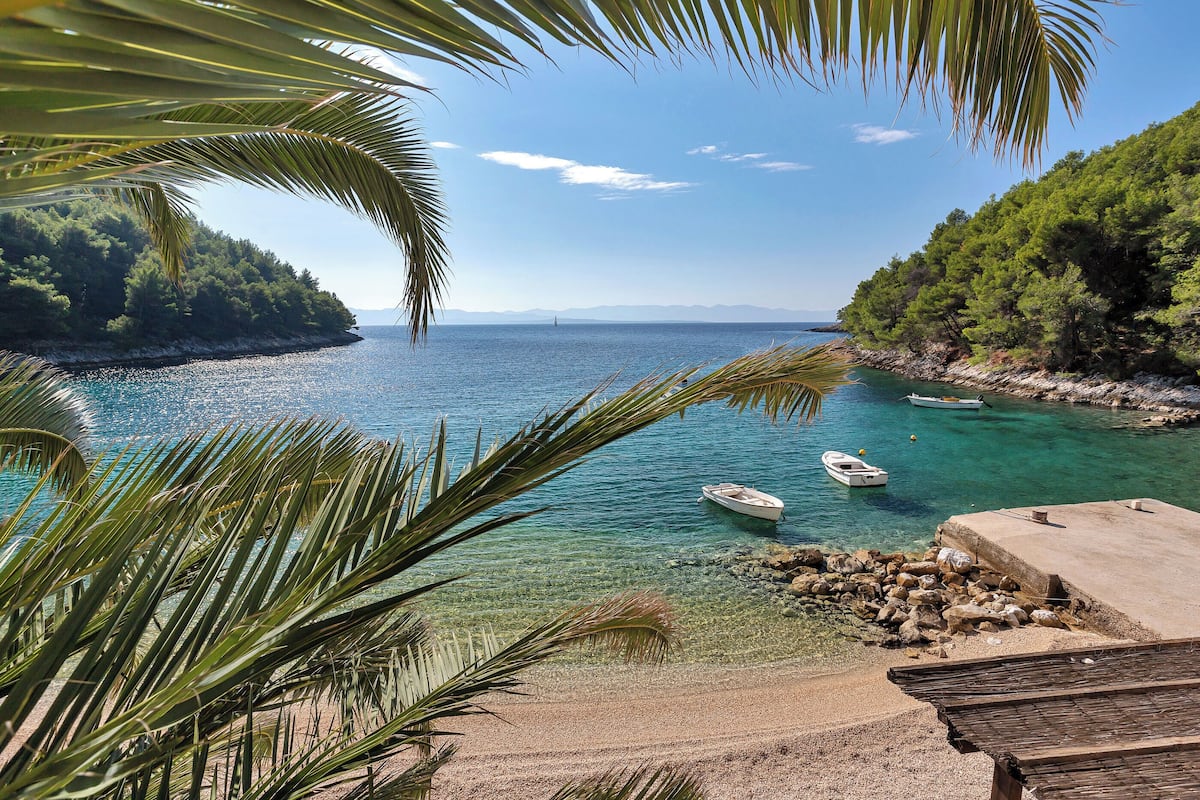 A coastal view with clear water, boats, and a rocky shoreline.