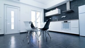A modern kitchen with white cabinets, a built-in oven, and a black countertop. - Apartments Annela (Seget)