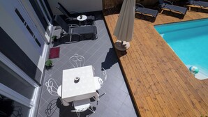 An outdoor patio with a pool, including a table and chairs, and a wooden deck. - Apartments Annela (Seget)