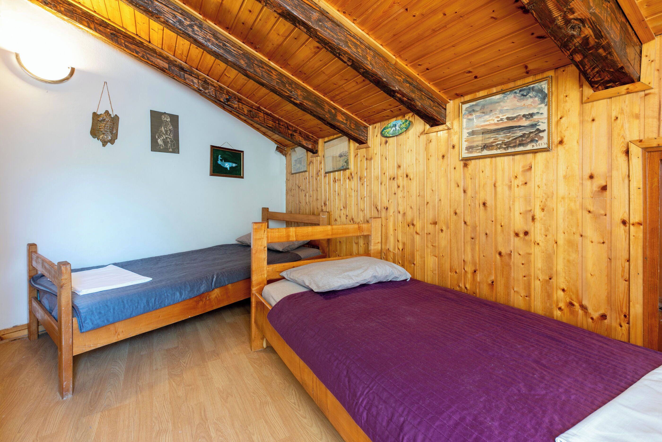 A wooden cabin with two bunk beds, wooden walls, and a sloped ceiling.