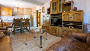 A spacious living room with a leather sofa, a glass coffee table, wooden cabinets, and a television. - Apartments Tatjana (Novi Vinodolski)