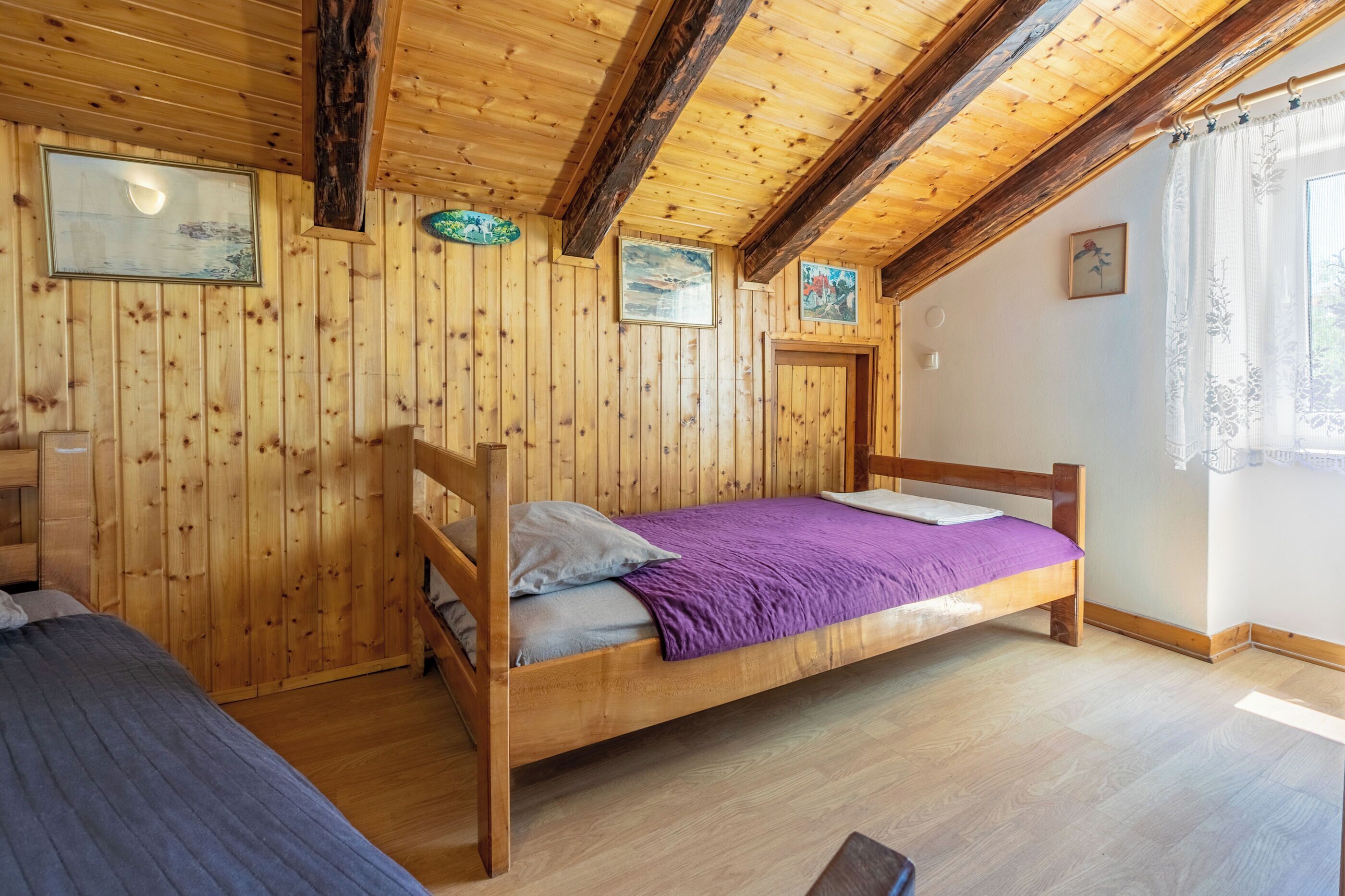 Une pièce de style cabane en bois, avec deux lits, des murs en bois et un plafond en pente.