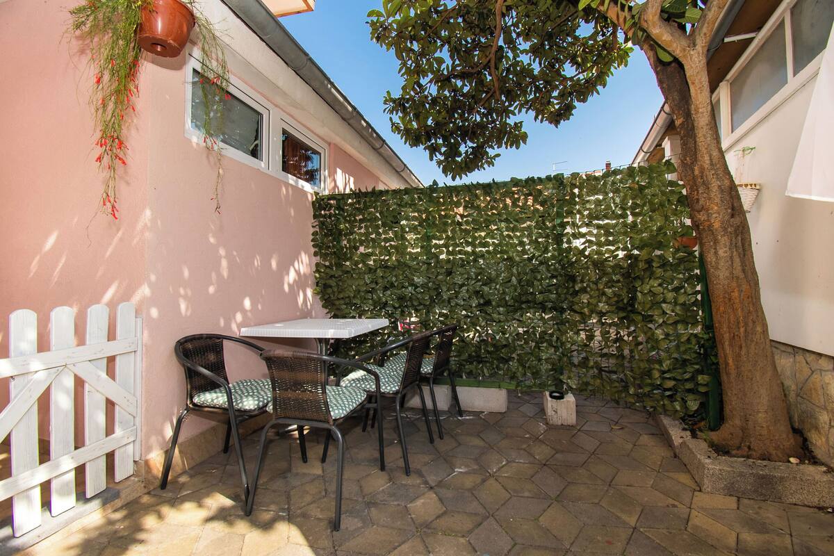 A patio area with a white fence, a table, and chairs.