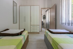 A bedroom with two beds, a wardrobe, and a television. - Apartment Danijel (Novi Vinodolski)