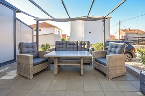 An outdoor patio with wicker furniture, a glass-top table, and a covered area. - Apartment Martin (Biograd na Moru)