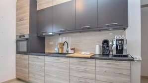 Una cucina moderna con pensili scuri, un piano di lavoro in legno e un forno integrato.