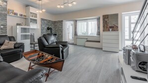 Een moderne woonkamer met een bank, een salontafel, een open haard en een groot raam.