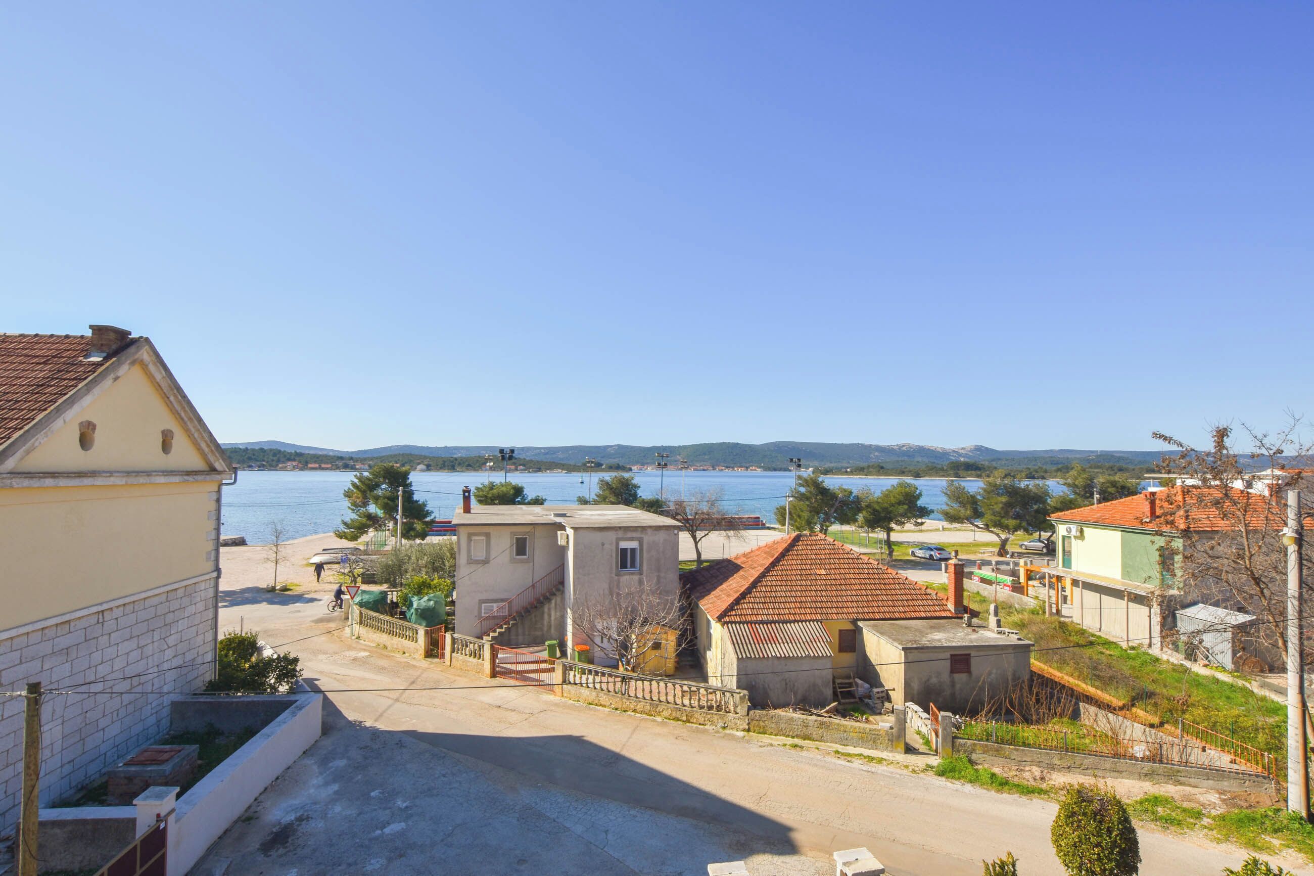 Un village côtier avec des bâtiments, un ciel dégagé et une vue sur la mer.