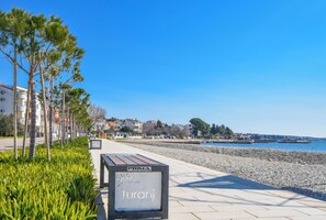 A seaside promenade with a sign reading "Turanj" and a view of the sea and buildings in the background. - Apartment Sterna (Sveti Filip i Jakov)