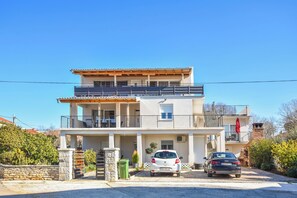 Uma casa moderna de dois andares com varanda, garagem e uma bandeira vermelha no telhado.