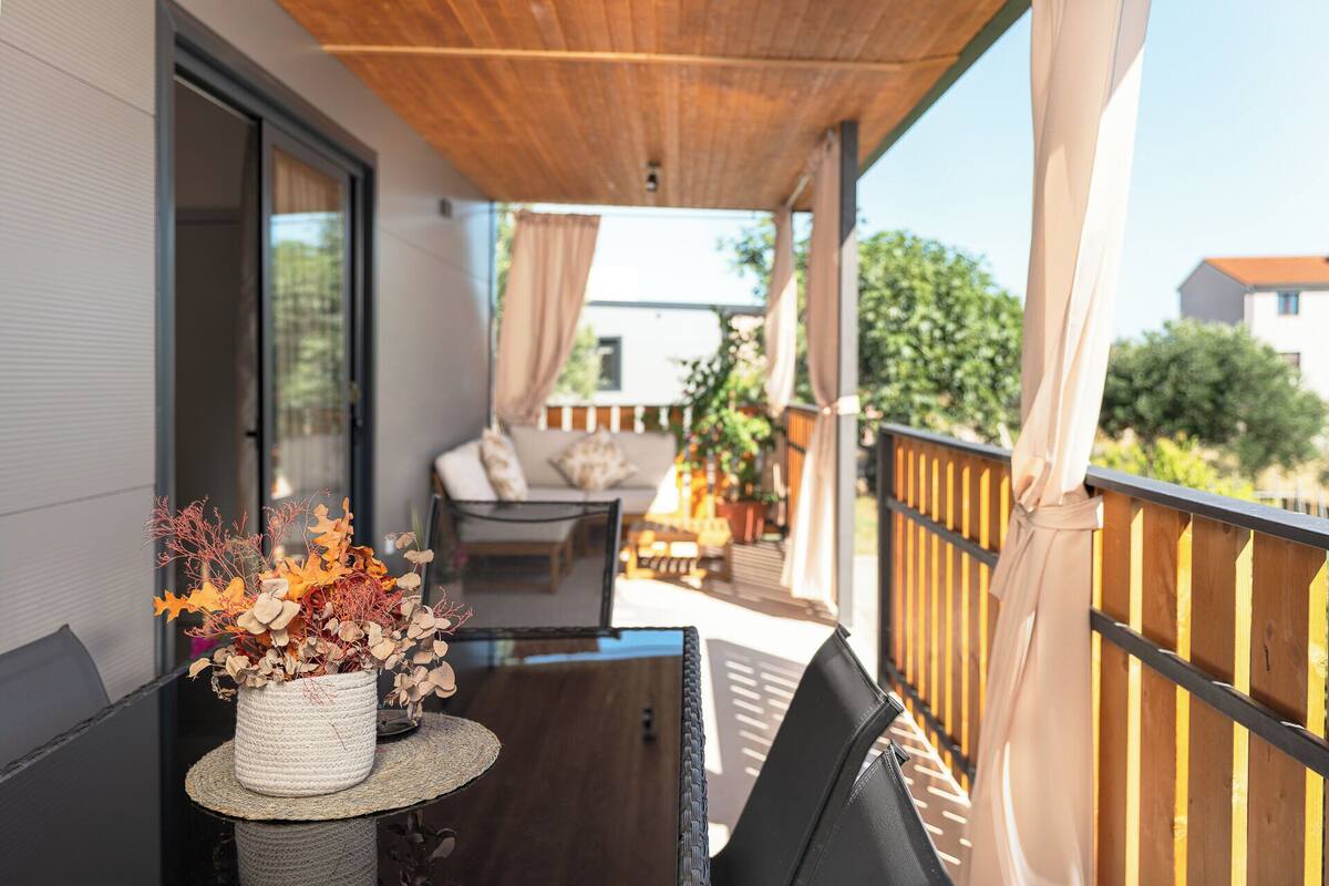 Een overdekt balkon met een tafel, stoelen en een bloempot.