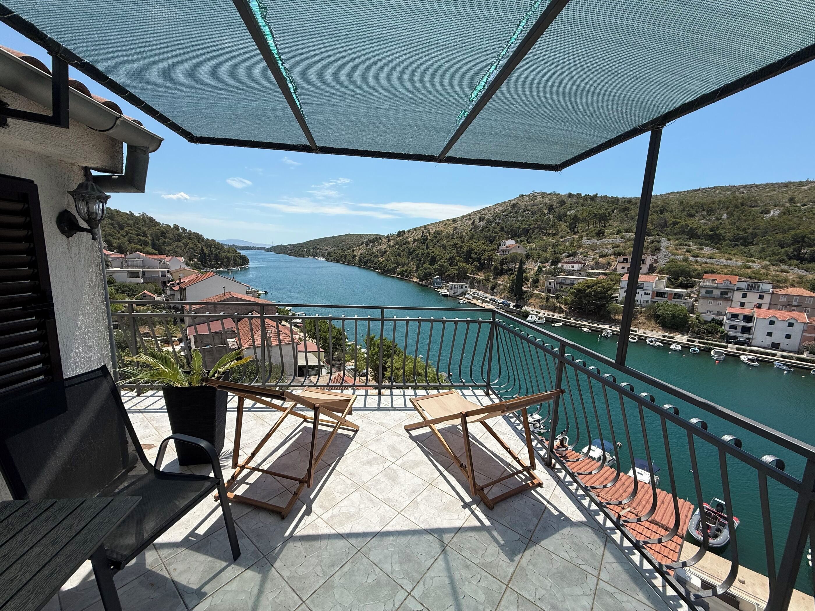Ein Balkon mit Blick auf einen Fluss, einem Stuhl und einem Blumentopf.