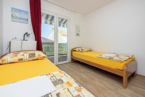 A room with two beds, a radiator, a desk, and a window with curtains. - Apartment Klemi (Crikvenica)