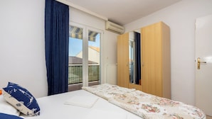 Un dormitorio con cama, armario y ventana con cortinas.