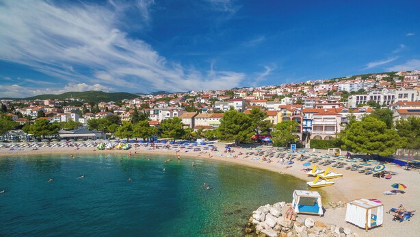 A coastal town with a beach, clear water, and buildings in the background. - Apartments Faran (Crikvenica)