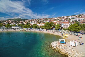 A coastal town with a beach, clear water, and buildings in the background. - Apartments Faran (Crikvenica)