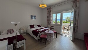 A bedroom with a bed, bedside table, lamp, and a view of the outdoors through a window. - Apartments Faran (Crikvenica)