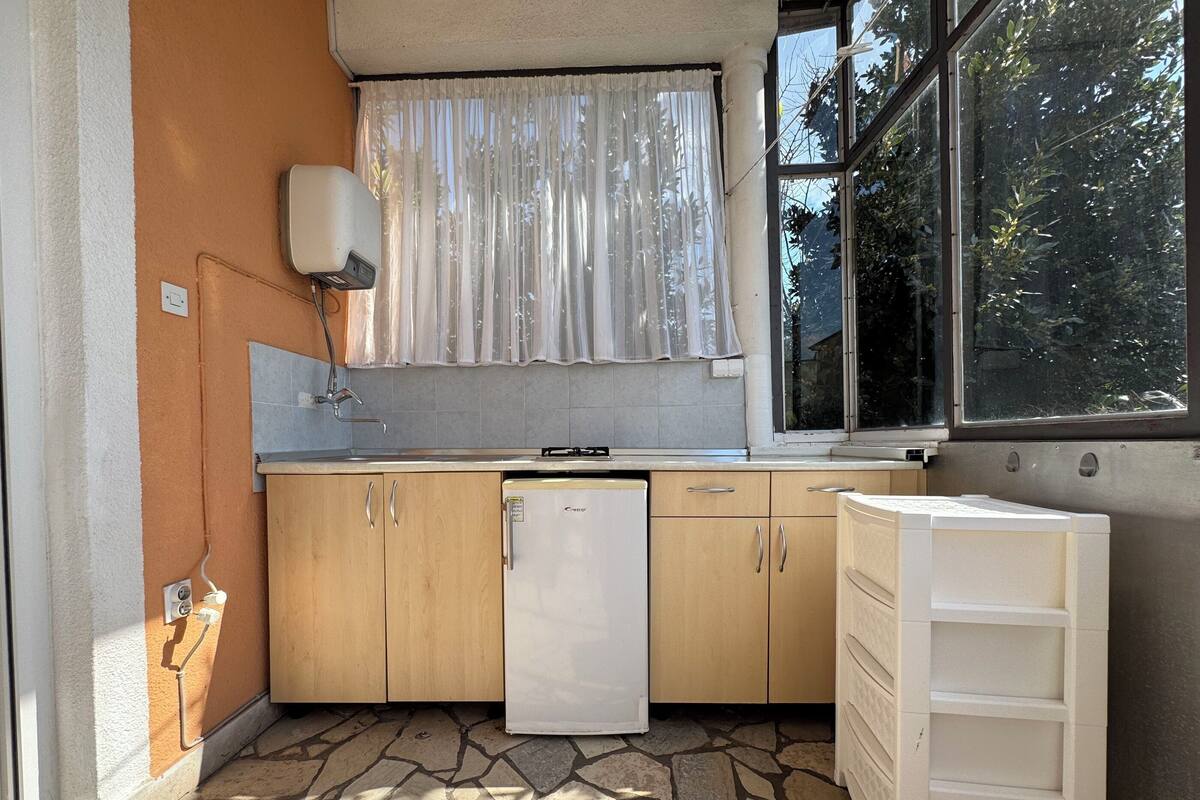 A compact kitchen with a refrigerator, sink, and window.