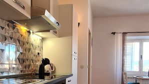 Eine moderne Küche mit weißen Schränken, einer Edelstahl-Spüle und einer gefliesten Rückwand.