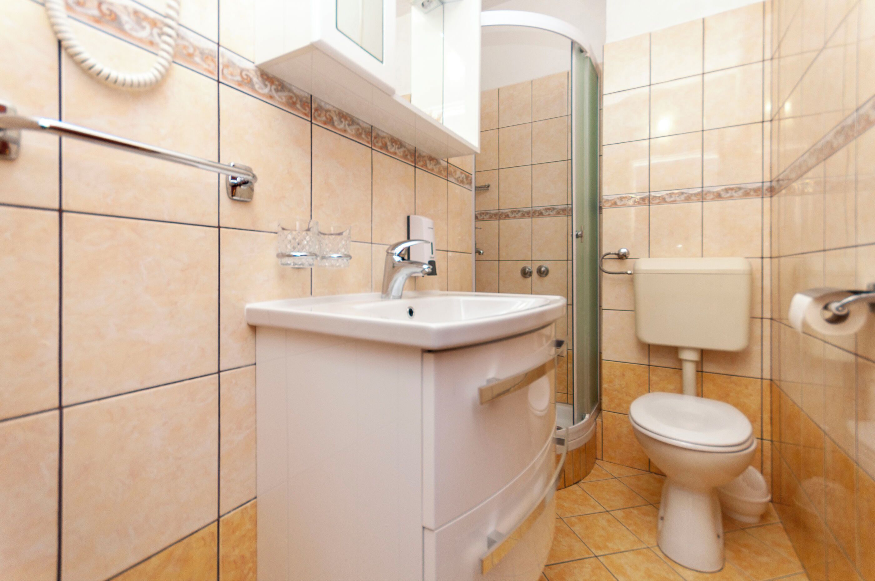 Un bagno con lavandino, water e doccia, tutti in bianco.