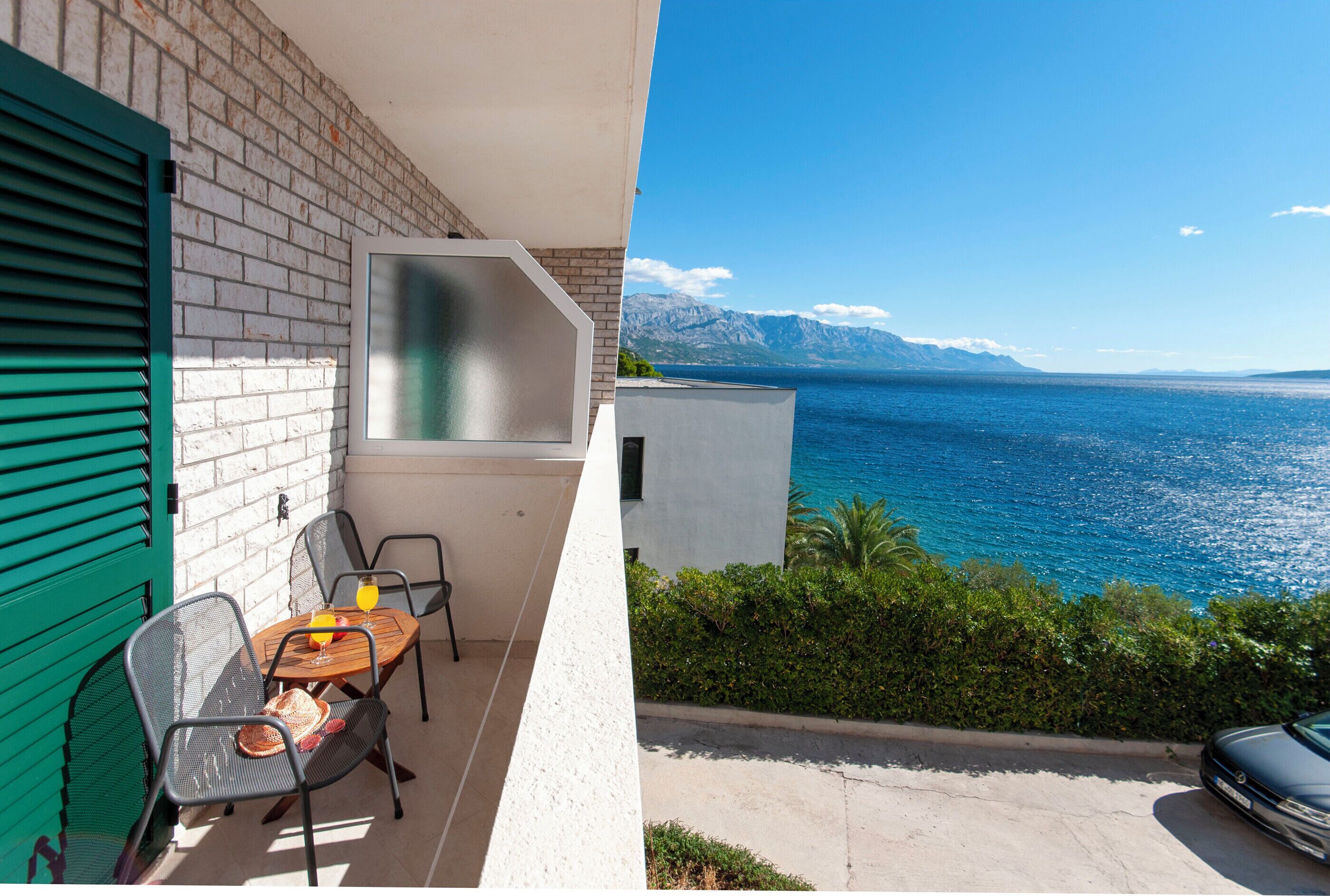 A balcony with a table, chairs, and a glass of orange juice.