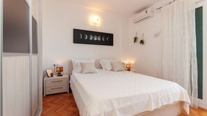 Een slaapkamer met een bed, nachtkastjes, een kunstwerk aan de muur en een airconditioning.