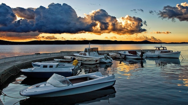 A marina with several boats docked, calm water, and a sunset with clouds in the background. - Apartments Dandelion (Biograd na Moru)