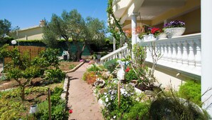 A garden pathway leading to a building with a white balcony. - Apartments Dandelion (Biograd na Moru)