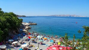 A beach with people, umbrellas, and boats. - Apartment Alej (Senj)