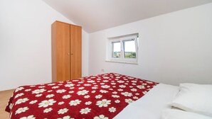 A bedroom with a bed, a wooden wardrobe, and a window. - Apartments Nikola (Nin)