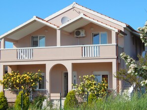 A two-story building with balconies, a central archway, and a red-tiled roof. - Apartments Nikola (Nin)