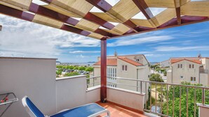 A balcony with a view of a residential area, a table with a chair, and a drying rack. - Apartments Jacqueline (Pakostane)