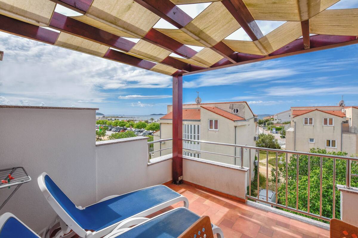 A balcony with a view of a residential area, a table with a chair, and a drying rack.