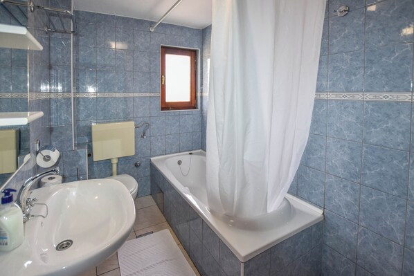 Ein Badezimmer mit Waschbecken, Spiegel, Toilette und Badewanne.