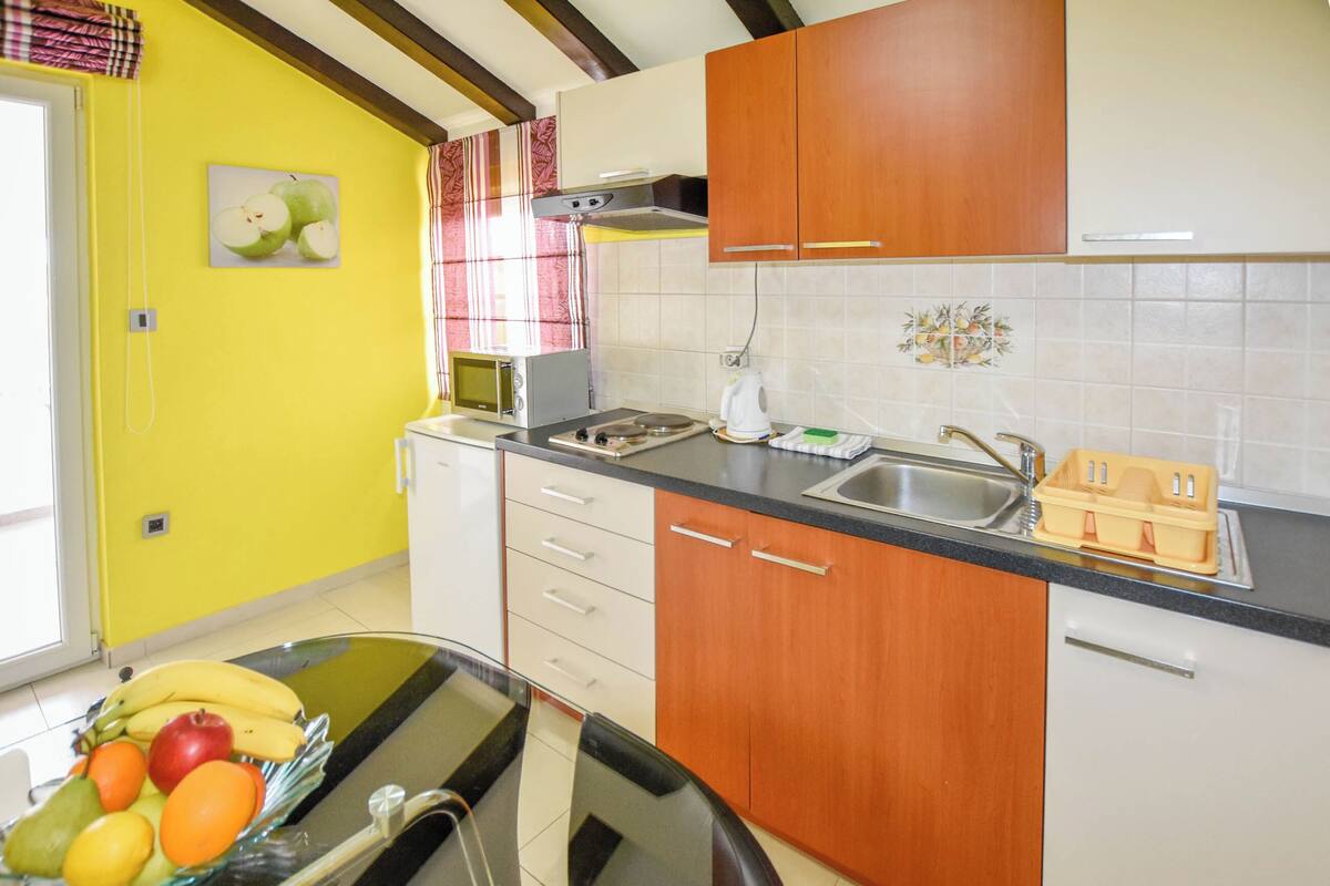 A kitchen with yellow walls, wooden cabinets, a black countertop, a sink, and a fruit bowl.