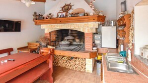A rustic kitchen with a brick oven, wooden furniture, and a tiled backsplash. - Apartments Jacqueline (Pakostane)