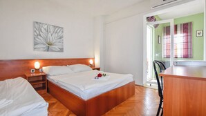 A bedroom with a wooden bed, bedside tables, a nightstand, a wall-mounted artwork, and a view of a green room through an open door. - Apartments Jacqueline (Pakostane)
