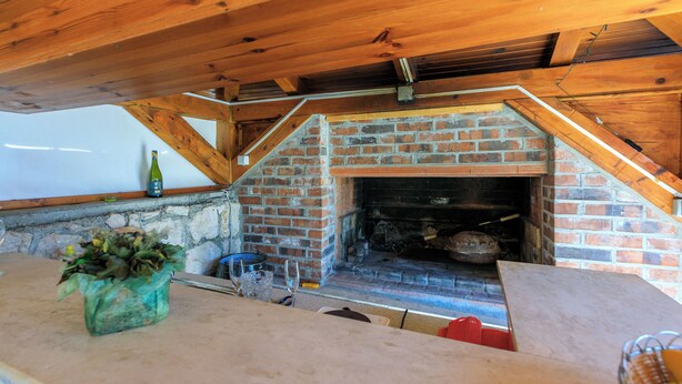 Cocina de estilo ático con chimenea de ladrillo, vigas de madera y pared de piedra.