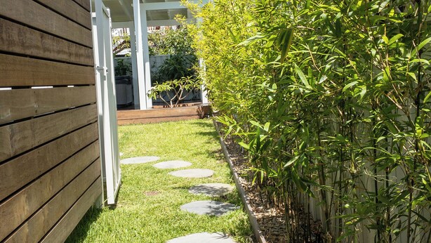 A garden pathway with stepping stones, a wooden fence, and a bamboo plant. - Studio11@Vincentia offers a quiet, intimate escape designed for pure relaxation. (Vincentia)