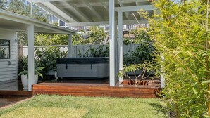 A backyard with a covered patio, a BBQ area, and a stone pathway. - Studio11@Vincentia offers a quiet, intimate escape designed for pure relaxation. (Vincentia)