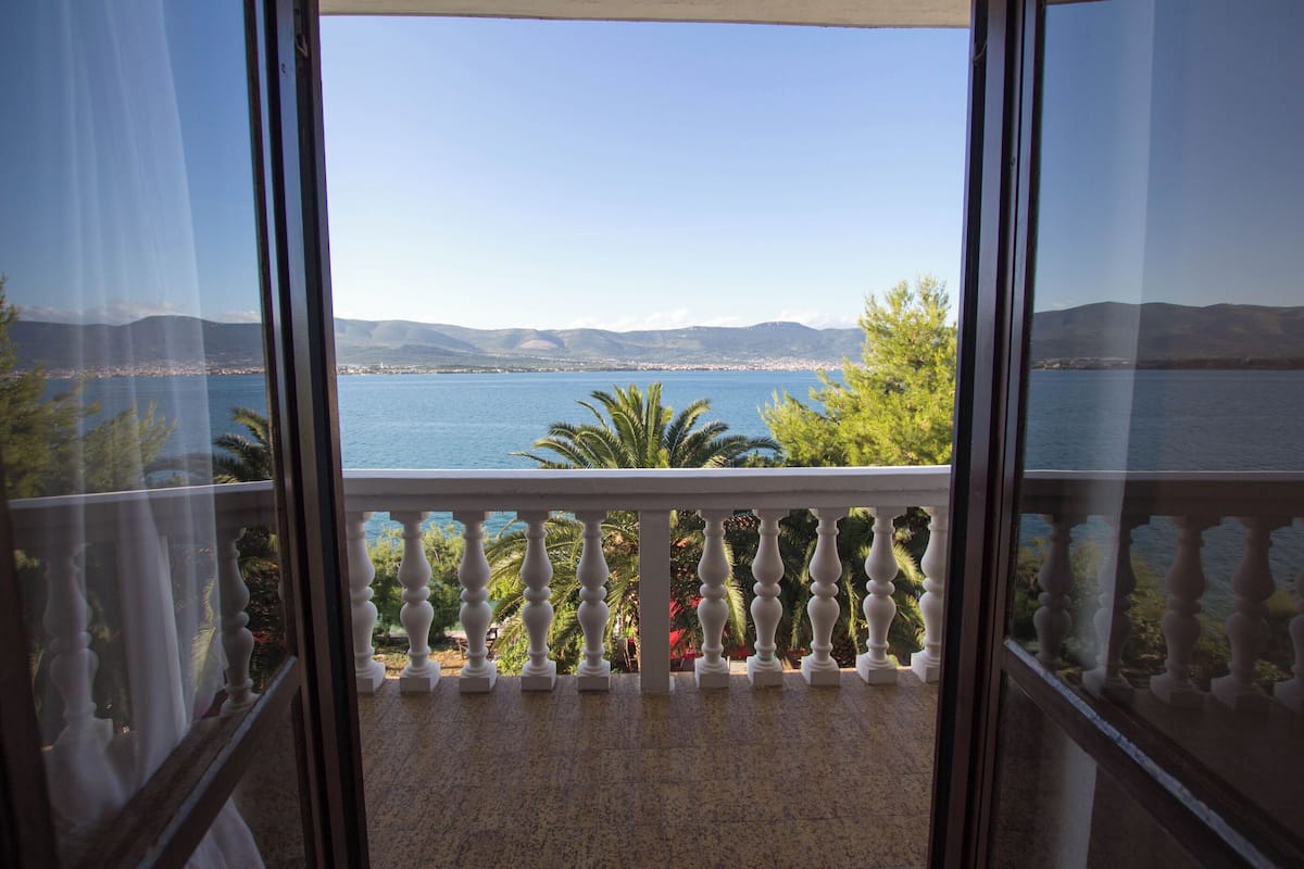 Un balcon avec vue sur une étendue d’eau et des montagnes lointaines.