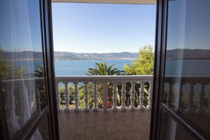 Un balcón con vista a un cuerpo de agua y montañas distantes.