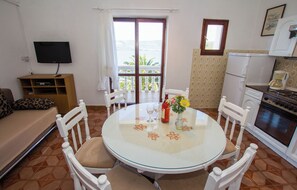 Un comedor con una mesa redonda, sillas blancas y vistas al mar a través de un ventanal grande.