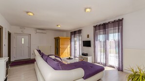 En moderne stue med en hvid sofa, et lille bord og et fjernsyn.