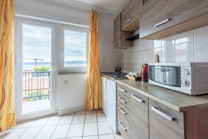 Eine moderne Küche mit Holzschränken, einer Mikrowelle und Blick aus dem Fenster.